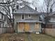 A two-story house with boarded windows and a small backyard at 3609 E Washington St, Indianapolis, IN 46201