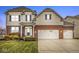 Two-story brick and beige home with a three-car garage and well-manicured lawn at 7648 Three Arch Overlook, Noblesville, IN 46062