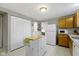 Galley kitchen with wood cabinets, white appliances & kitchen island at 6018 Thrushwood Dr, Indianapolis, IN 46250