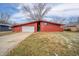 Ranch style home with red exterior, attached garage, and mature trees at 827 Bittersweet Ln, Anderson, IN 46011