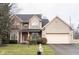 Two-story brick and beige house with a red door, attached garage, and landscaped lawn at 7589 Willow Rdg, Fishers, IN 46038