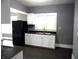 White kitchen cabinets, black appliances, and dark gray walls at 1314 Arrow Ave, Anderson, IN 46016
