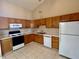 Galley kitchen with oak cabinets, white appliances, and tile floor at 7254 Broyles Ln, Indianapolis, IN 46217