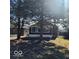 Cute bungalow with a covered porch, partially visible from behind trees at 3949 English Ave, Indianapolis, IN 46201