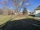 Large backyard with mature trees and a partially visible house at 102 N Munsie St, Indianapolis, IN 46229