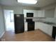 Modern kitchen with white cabinets, black appliances, and laminate flooring at 515 Churchman Ave, Beech Grove, IN 46107