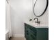 Bathroom with a dark green vanity and a large round mirror at 849 N Oakland Ave, Indianapolis, IN 46201