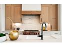 Sleek kitchen featuring a gas range, marble backsplash, and light oak cabinets at 41 N Rangeline Rd # 2, Carmel, IN 46032