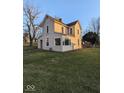 Two-story house with light beige siding, a large yard, and mature trees at 213 E Broadway St, Alexandria, IN 46001