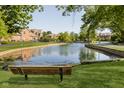 Serene pond with a wooden bench, surrounded by lush greenery and brick buildings at 8751 Jaffa Court E Dr # 35, Indianapolis, IN 46260