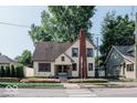 Full exterior view of a charming two-story house with a brick chimney and well-maintained lawn at 819 E 49Th St, Indianapolis, IN 46205