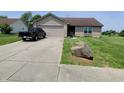 Tan brick ranch home with a black truck parked in the driveway and a large rock at 1096 Bumblebee Way, Greenfield, IN 46140