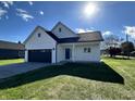 White farmhouse exterior with a dark gray roof and a two-car garage at 1692 Victor Dr, Martinsville, IN 46151