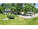 Stone house with a large tree and gravel driveway at 11445 N School St, Fishers, IN 46038