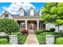 Brick front home with a large covered porch and manicured landscaping at 15482 Bridgewater Club Blvd, Carmel, IN 46033
