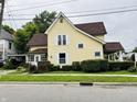 Yellow house with brown roof, landscaping, and porch at 202 N State St, Greenfield, IN 46140