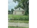 A beige house with damaged siding and a chain link fence in the front yard at 2515 S Lockburn St, Indianapolis, IN 46241