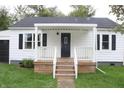 White house with a covered porch, black door, and well-manicured lawn at 2312 E 22Nd St, Muncie, IN 47302