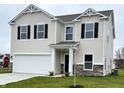 Two-story house with beige vinyl siding, stone accents, and a two-car garage at 3568 Berkdale Dr, Columbus, IN 47203