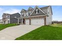 Two-story home with gray siding and brick accents, three-car garage, and a large driveway at 4959 Amber Crest Dr, Brownsburg, IN 46112