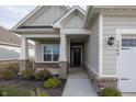 Front entrance with covered porch, brick columns, and landscaping at 1569 Tupelo Dr, Greenfield, IN 46140