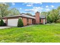 Brick ranch home with attached two-car garage and manicured lawn at 9263 Golden Oaks W, Indianapolis, IN 46260