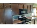 Dark wood cabinets, microwave, and electric range in this kitchen at 2721 Del Prado Dr, Indianapolis, IN 46227