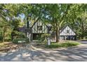 Tudor style home with black and white exterior, landscaping, and large trees at 6470 Around The Hills Rd, Indianapolis, IN 46226
