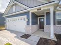 Close-up of the front entrance of a blue and gray home with a white front porch and dark brown door at 5628 Cattail Branch Ln, Clayton, IN 46118