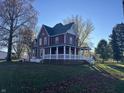 Side view of a charming two-story red house with white trim and a deck at 503 E Clyde St, Frankton, IN 46044