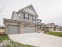 Two-story house with gray siding, brick accents, and a three-car garage; view of neighboring houses at 259 Lar Lan Dr, Danville, IN 46122