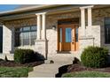Inviting front entrance with a wood door, brick columns, and landscaping at 7290 Lockford Walk N, Avon, IN 46123