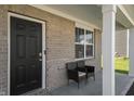 Brick front porch with a black front door and two wicker chairs at 10797 Walden Ln, Brownsburg, IN 46112