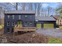 Two-story dark exterior home with green garage doors, deck, and basketball hoop at 10455 Courageous Dr, Indianapolis, IN 46236