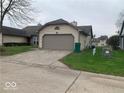 Beige one car garage with driveway and grassy yard at 4112 Eagle Cove E Dr, Indianapolis, IN 46254