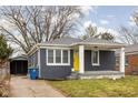 Gray brick house with yellow door, covered porch, and detached shed at 5114 Hillside Ave, Indianapolis, IN 46205