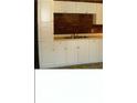 White kitchen cabinets, brick backsplash, and double sink at 3726 N Emerson Ne Ave, Indianapolis, IN 46218