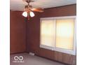 Simple living room with wood paneling, ceiling fan, and window blinds at 3726 N Emerson Ne Ave, Indianapolis, IN 46218