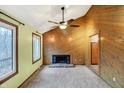 Living room with wood-paneled walls, a fireplace, and large windows offering natural light at 13832 W Old Nashville Rd, Columbus, IN 47201