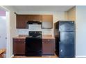 Kitchen with black appliances, brown cabinets, and wood-look flooring at 10938 Delphi Dr, Camby, IN 46113