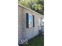 Side view of the house showcasing tan brick exterior and dark shutters at 3716 N Emerson Ne Ave, Indianapolis, IN 46218