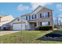 Two-story house with brick and vinyl siding exterior, attached garage, and landscaped yard at 6415 Kelsey Dr, Indianapolis, IN 46268