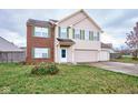 Two-story house with brick and beige siding, two-car garage, and landscaped yard at 8231 Golden Ridge Ln, Indianapolis, IN 46237
