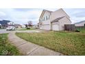 Two-story house with beige siding, two-car garage, and a side yard at 8231 Golden Ridge Ln, Indianapolis, IN 46237