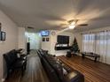 Living room with wood-look floors, black leather furniture, and a large TV at 2941 Earlswood Ln, Indianapolis, IN 46217