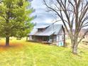 Rustic log cabin with a covered porch and metal roof, nestled in a green lawn at 7021 Bellsville Pike, Columbus, IN 47201