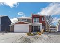 Two-story home with red and beige exterior, snow-covered lawn, and attached garage at 610 Atlas Dr, Lebanon, IN 46052