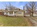 Charming yellow bungalow with a covered front porch and attached garage at 6440 Maple St, Indianapolis, IN 46236