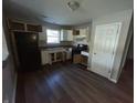 Compact kitchen with white cabinetry, black appliances, and wood-look flooring at 6215 E 11Th St, Indianapolis, IN 46219