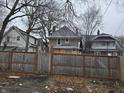 Rear view of a house with a wooden fence and leaf covered yard at 3609 E Washington St, Indianapolis, IN 46201